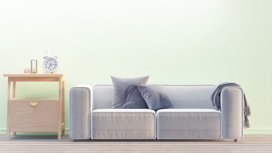 A cozy minimalist living room with a modern sofa, side table, and alarm clock.